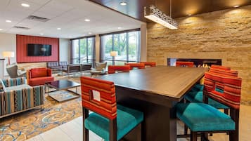 A conference room with a long table, red and teal chairs, a fireplace, and a stone wall.