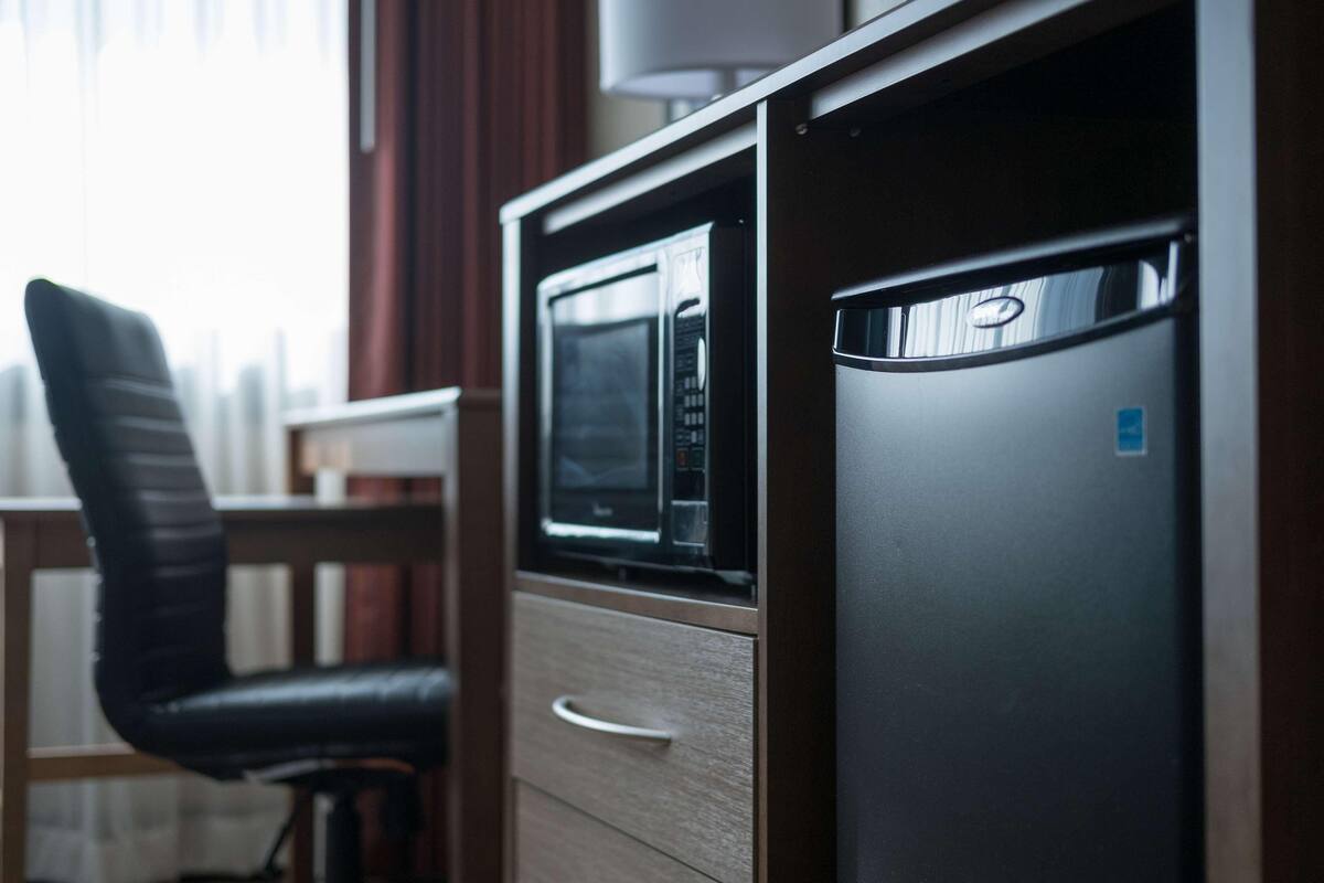A compact kitchenette with a microwave, a refrigerator, and a chair.