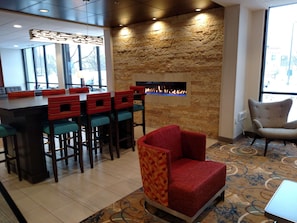 A bar area with stools, a fireplace, and a patterned carpet. - Radisson Hotel St. Paul Downtown (St. Paul)