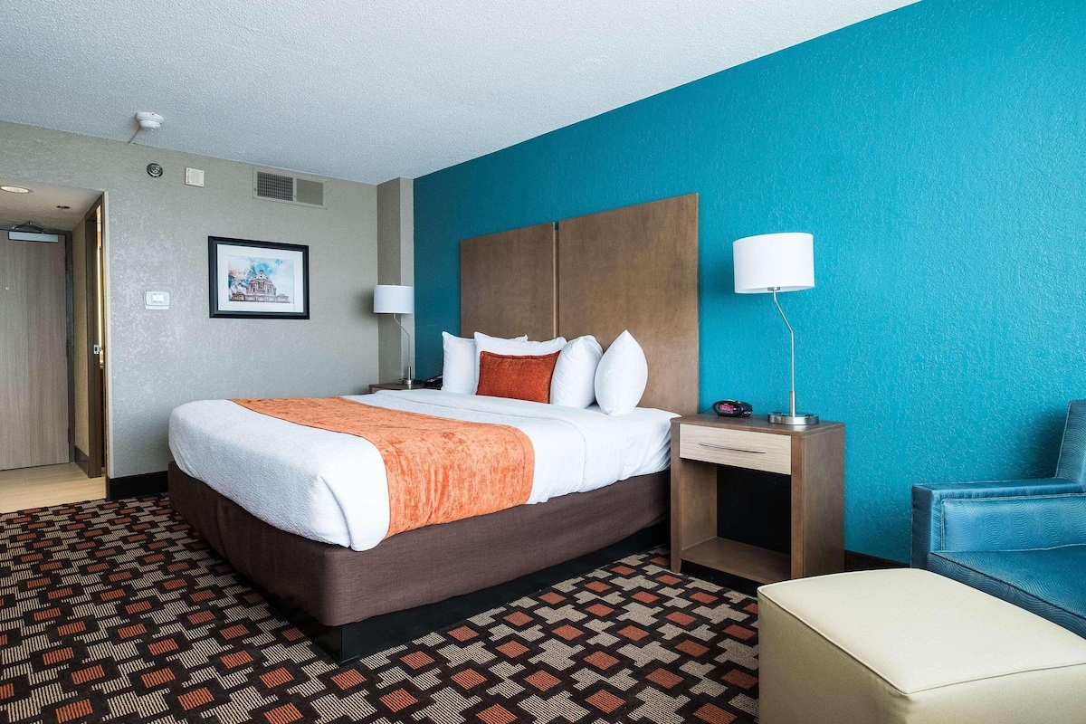 Une chambre d’hôtel équipée d’un lit, d’un bureau, d’une chaise et d’une lampe fixée au mur.