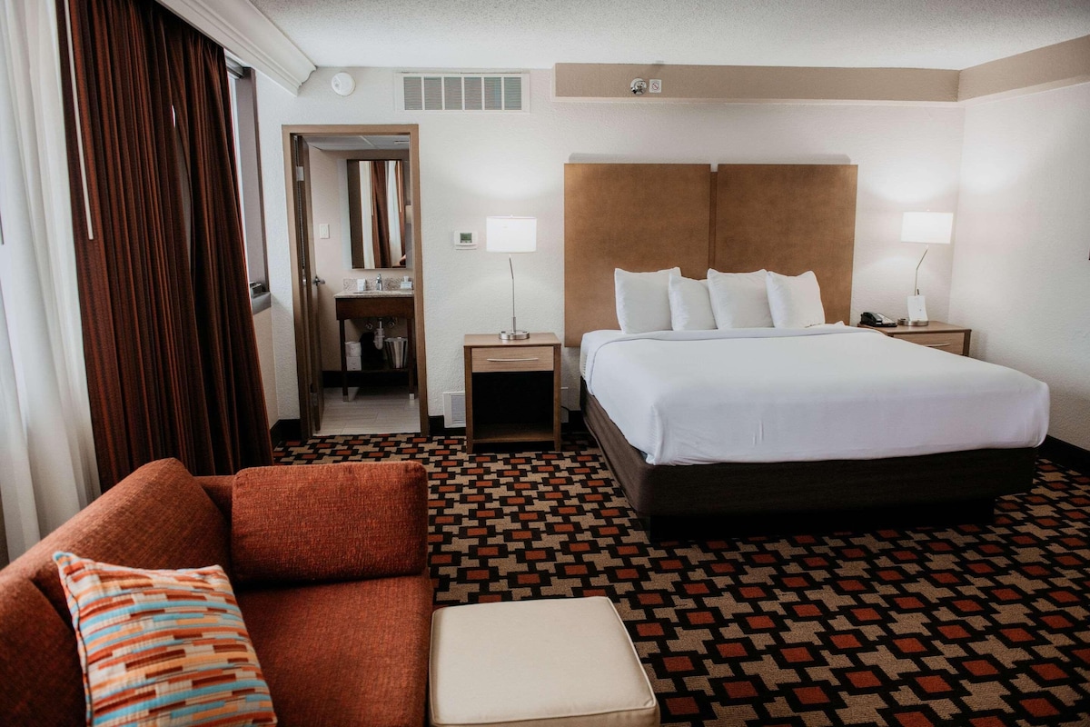 Une chambre d’hôtel avec un grand lit, un canapé, une petite table et un miroir.