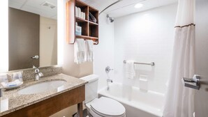 Un bagno con lavandino, WC, vasca, tenda per doccia e uno specchio con ripiano sopra.