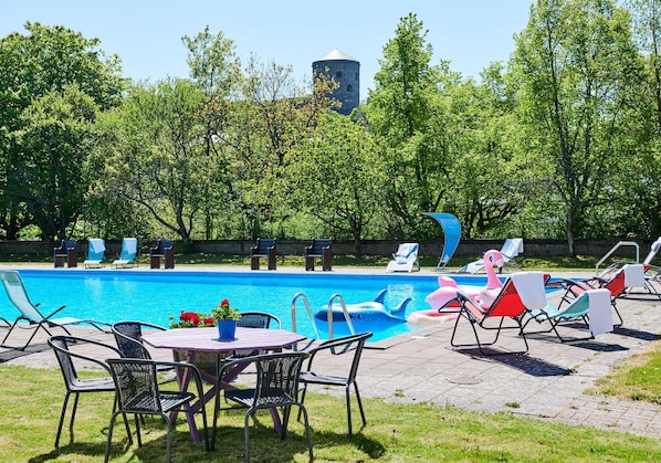 A swimming pool with lounge chairs, a table with chairs, and a water tower in the background. - Radisson Hotel St. Paul Downtown (St. Paul)