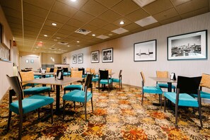 A hotel conference room with tables, chairs, and framed pictures on the walls. - Radisson Hotel St. Paul Downtown (St. Paul)