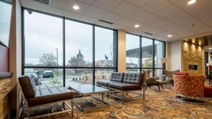 Un hall d’hôtel doté de grandes fenêtres, d’une cheminée, d’un espace salon et d’un tapis à motifs.