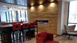 Un espace bar avec des tabourets, une cheminée et une moquette à motifs.