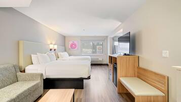 A hotel room with a bed, a sofa, a desk, a bench, a TV, and a window with a view.