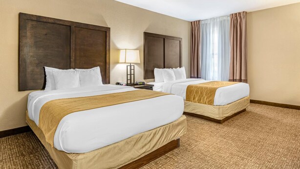A hotel room with two beds, a nightstand, a lamp, and a window with curtains. - Best Western Lubbock West Inn and Suites (Lubbock)