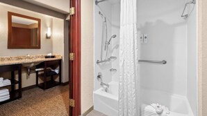 A modern bathroom with a bathtub, shower, and a vanity with a mirror and sink. - Best Western Lubbock West Inn and Suites (Lubbock)