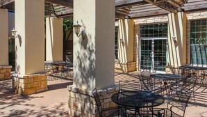 An outdoor patio with multiple tables and chairs, stone pillars, and a pergola structure. - Best Western Lubbock West Inn and Suites (Lubbock)
