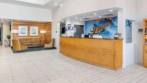 A reception area with a wooden reception desk, a sofa, and a wall with a 'Welcome to Lybock' sign. - Best Western Lubbock West Inn and Suites (Lubbock)