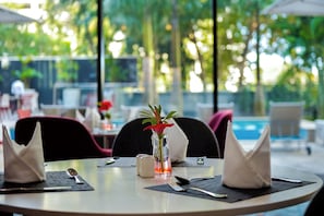 A dining table with a vase of flowers, a salt shaker, and cutlery. - Crowne Plaza Dar Es Salaam (Dar es Salaam)