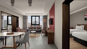 A modern hotel room with a dining area, a sofa set, a TV, and a bed. - Crowne Plaza Dar Es Salaam (Dar es Salaam)