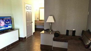 Una sala de estar con televisor, lámpara y sofá.