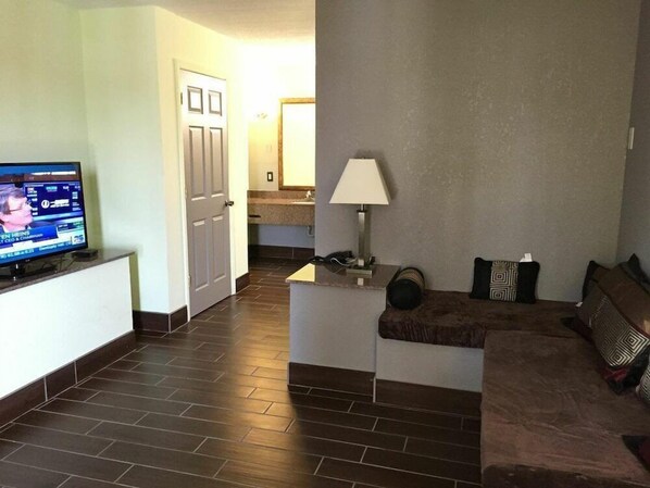 A living room with a television, a lamp, and a sofa. - Motel6 Stockbridge, GA - Hwy 138 W (Stockbridge)