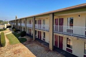 Un motel con una fila de habitaciones, cada una con balcón y puerta.