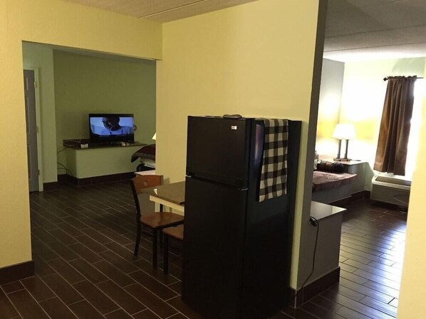 Een compacte hotelkamer met een kitchenette, een televisie, een klein eettafeltje en een stoel.