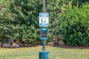 A pet waste station with a sign instructing to leash up and clean up after pets. - Motel6 Stockbridge, GA - Hwy 138 W (Stockbridge)