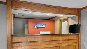 Een receptiebalie met een houten afwerking en een bordje met de tekst 'AMERICAS BEST VALUE INN'.
