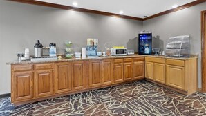 Een hotelkeuken met houten kastjes, een magnetron, koffiezetapparaat en een waterdispenser.