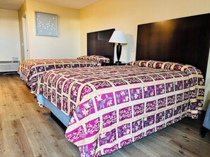 A hotel room with two beds, a dark headboard, a wall-mounted lamp, and a framed picture. - King City Motel by OYO Pasco (Pasco)