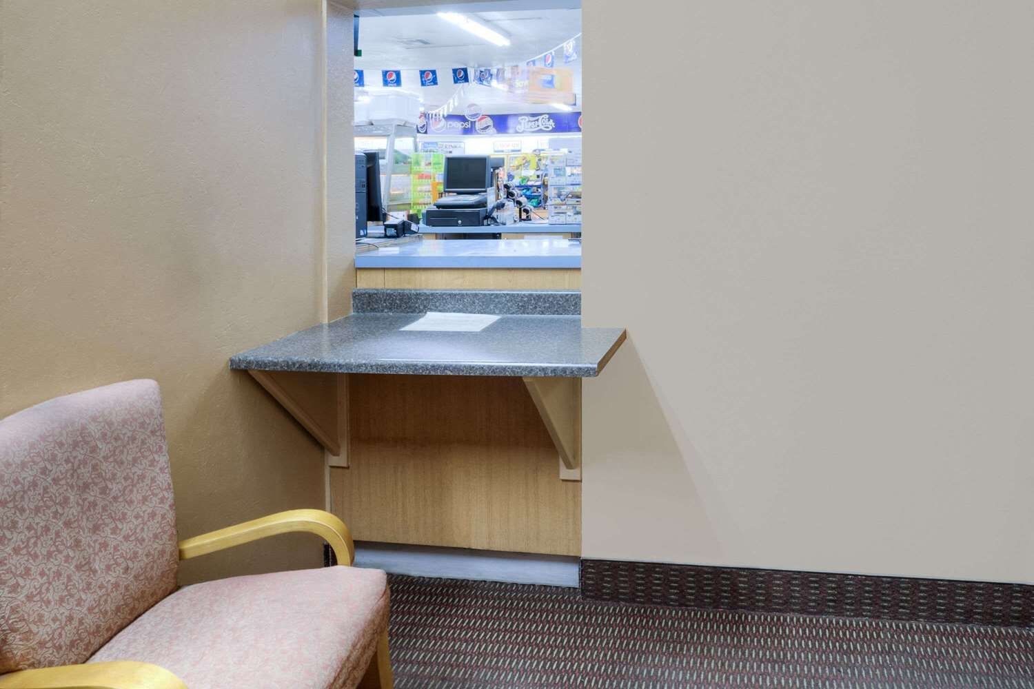 A corner of a room with a chair, a counter, and a vending machine area in the background.