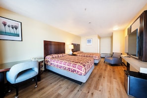 A hotel room with a bed, a desk, a chair, a TV, and a picture on the wall.