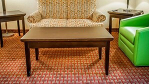 A hotel room with a patterned sofa, a green couch, a wooden coffee table, and two side tables with lamps. - Quality Inn & Suites Roswell (Roswell)