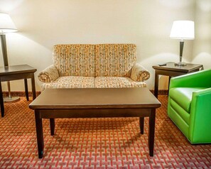 A hotel room with a patterned sofa, a green couch, a wooden coffee table, and two side tables with lamps. - Quality Inn & Suites Roswell (Roswell)