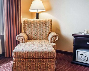 A hotel room with a patterned armchair, a desk with a telephone, and a lamp. - Quality Inn & Suites Roswell (Roswell)