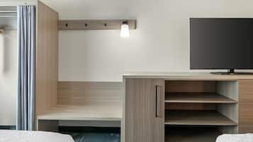 A hotel room with a bed, a desk, a television, and a light fixture.