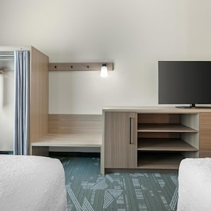 Una habitación de hotel con cama, escritorio, televisión y lámpara.