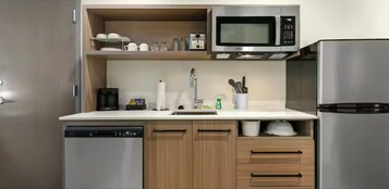 Una cocina moderna equipada con lavavajillas, microondas, refrigerador, armarios de madera y un lavamanos.