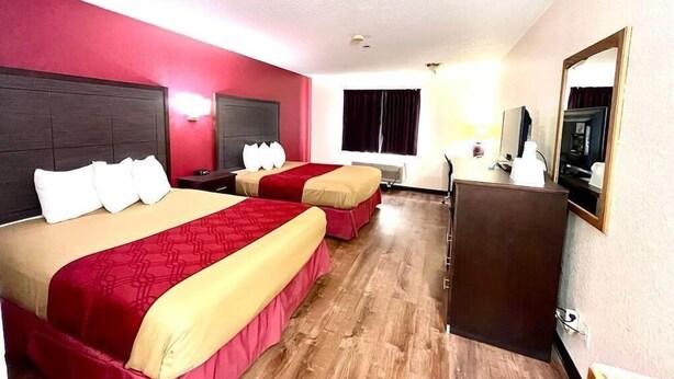 A hotel room with two beds, a desk, a television, and a mirror. - Econo Lodge Oacoma - Chamberlain West (Oacoma)