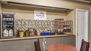 A breakfast area with a Daybreak sign, milk dispensers, coffee makers, and a bread display. - Vernon Motel (Vernon)