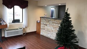 A room with a stone wall, a small Christmas tree, a window with curtains, and a radiator. - Red Roof Inn Kimball, TN - I-24 (South Pittsburg)