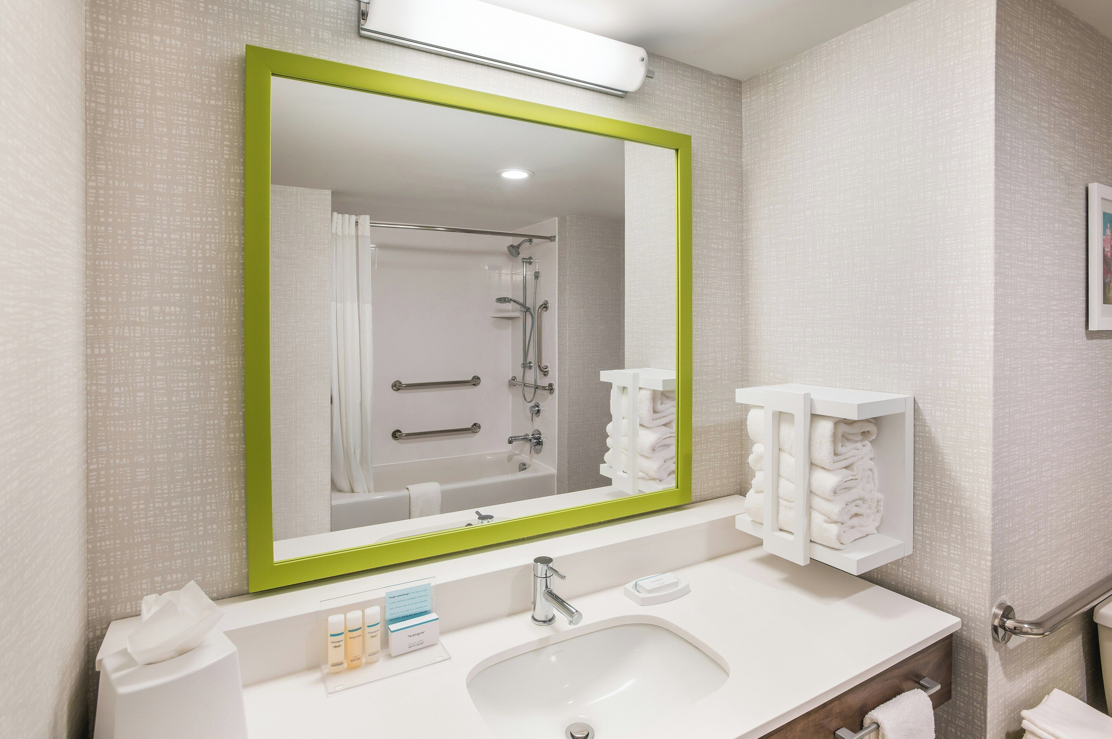 A bathroom with a large mirror, a sink, a towel rack, and a shower.