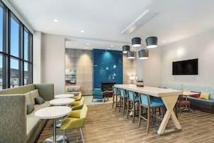 Un área lounge moderna con bar, asientos y chimenea.
