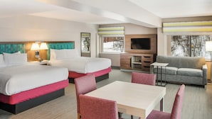A hotel room with two beds, a sofa, a TV, and a dining area. - Hampton Inn & Suites Houghton (Houghton)