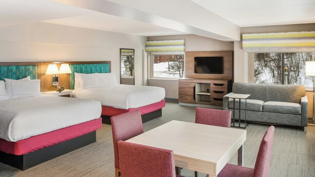 Habitación de hotel con dos camas, un sofá, un televisor y una zona de comedor.