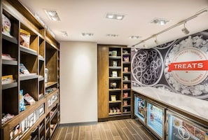 A well-lit snack and sundries section with shelves stocked with various snacks and a refrigerated display case. - Hampton Inn & Suites Houghton (Houghton)
