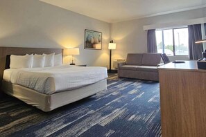A hotel room with a large bed, a sofa, a desk, and a window. - Edgewater Inn and Suites, Ascend Hotel Collection (Coos Bay)