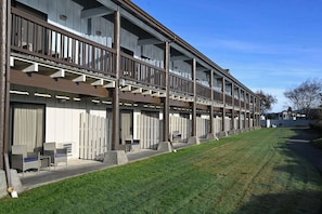 A multi-story hotel with balconies, outdoor seating, and a well-maintained lawn. - Edgewater Inn and Suites, Ascend Hotel Collection (Coos Bay)