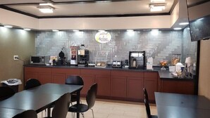 Un espace cuisine moderne doté d’un bar pour prendre le petit-déjeuner, équipé de machines à café et d’un panneau indiquant les heures du service du petit-déjeuner.