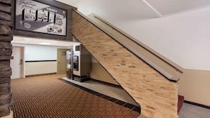 Un hall d’hôtel avec un escalier, un comptoir d’accueil et un panneau fixé au mur.