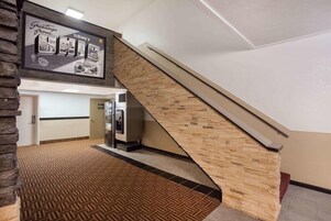 A hotel lobby with a staircase, a reception desk, and a wall-mounted sign.