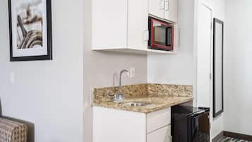 A compact kitchen with a granite countertop, a built-in microwave, and a sink.