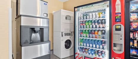 Una máquina expendedora con el logotipo de Coca-Cola, un dispensador de agua y una lavadora.
