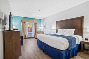 A hotel room with a large bed, a desk, a chair, and a television.