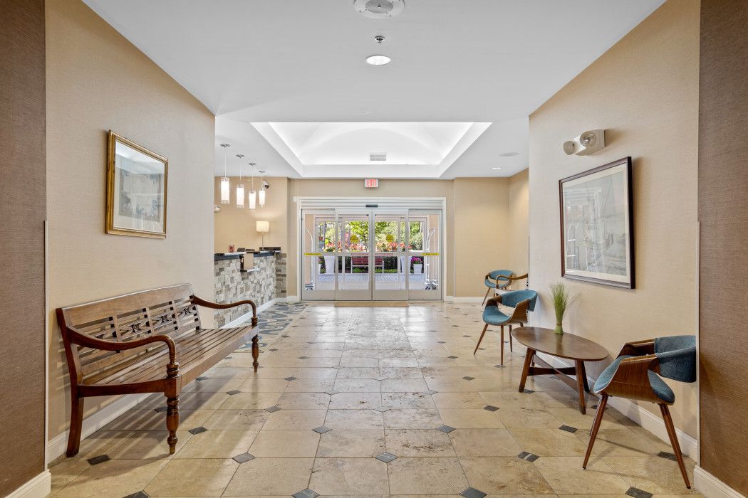 A hotel lobby with a wooden bench, a reception desk, and a glass door entrance.